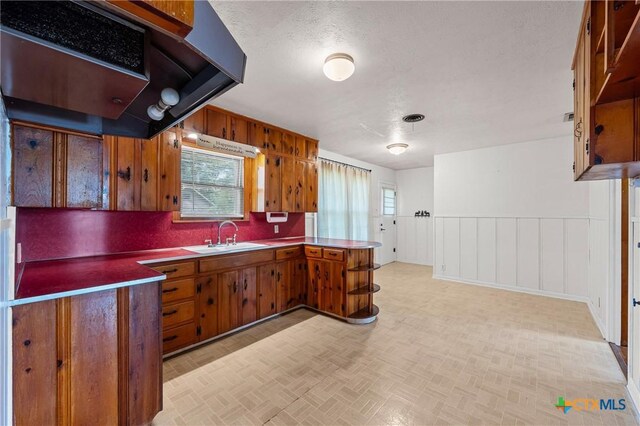 1820 S 49th St, Temple, TX 76504 - kitchen featuring brown cabinets, a peninsula, range hood, and light countertops