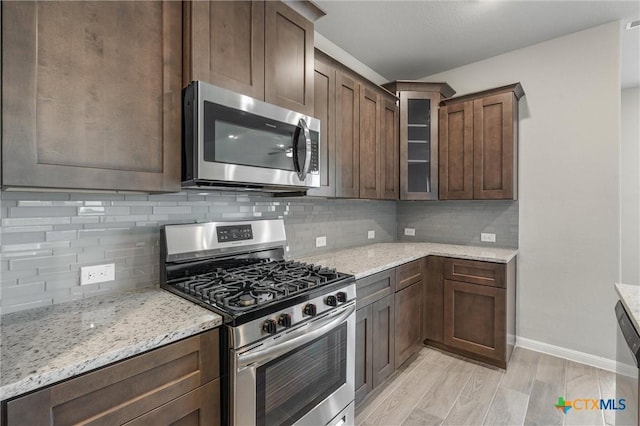 416 Stellar Wind Dr, Georgetown, TX 78628 - kitchen with light stone countertops, appliances with stainless steel finishes, and dark brown cabinetry