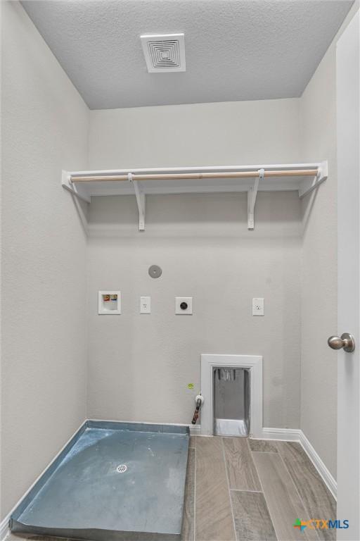 416 Stellar Wind Dr, Georgetown, TX 78628 - laundry room with wood-type flooring, hookup for a gas dryer, washer hookup, electric dryer hookup, and a textured ceiling
