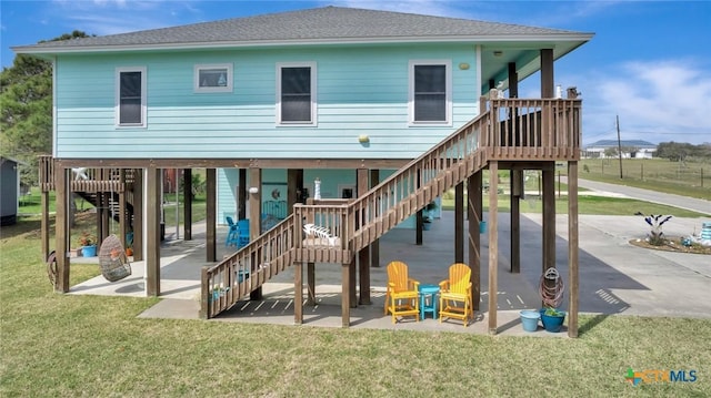 back of property with stairs, a patio, a yard, and a shingled roof