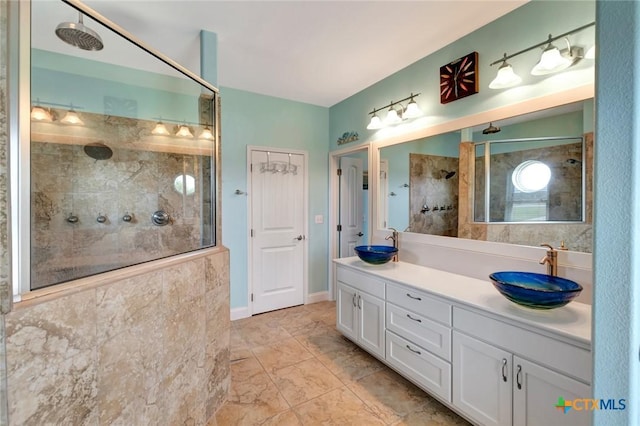 full bathroom featuring double vanity, tiled shower, baseboards, and a sink