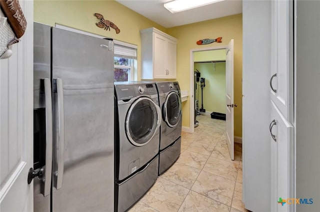 washroom featuring cabinet space, independent washer and dryer, marble finish floor, and baseboards