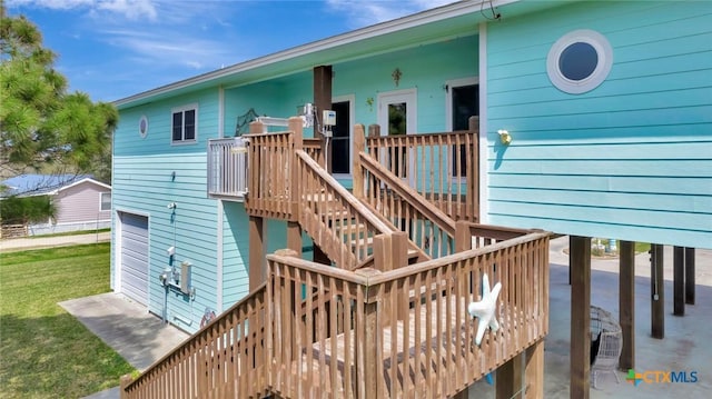 back of house with a yard, a deck, an attached garage, and stairway