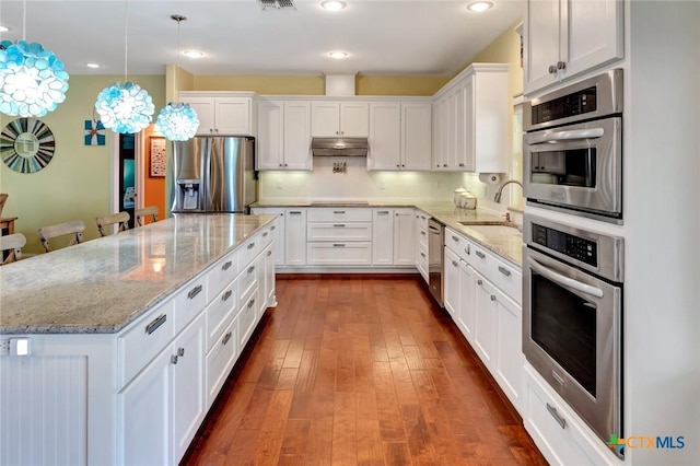 kitchen featuring a sink, stainless steel appliances, dark wood-type flooring, white cabinets, and under cabinet range hood