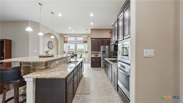 kitchen with a sink, appliances with stainless steel finishes, a breakfast bar, a spacious island, and light stone counters