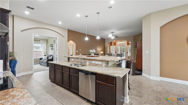 kitchen featuring stainless steel dishwasher, open floor plan, a sink, arched walkways, and dark brown cabinets