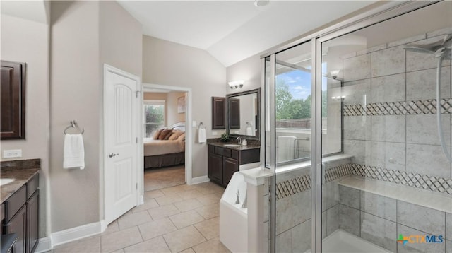 ensuite bathroom with vanity, a stall shower, vaulted ceiling, tile patterned flooring, and baseboards