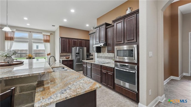 kitchen with stainless steel appliances, a sink, arched walkways, under cabinet range hood, and backsplash