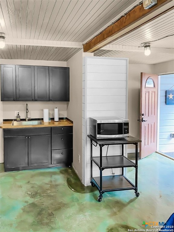 kitchen featuring concrete flooring, sink, wood counters, and beam ceiling