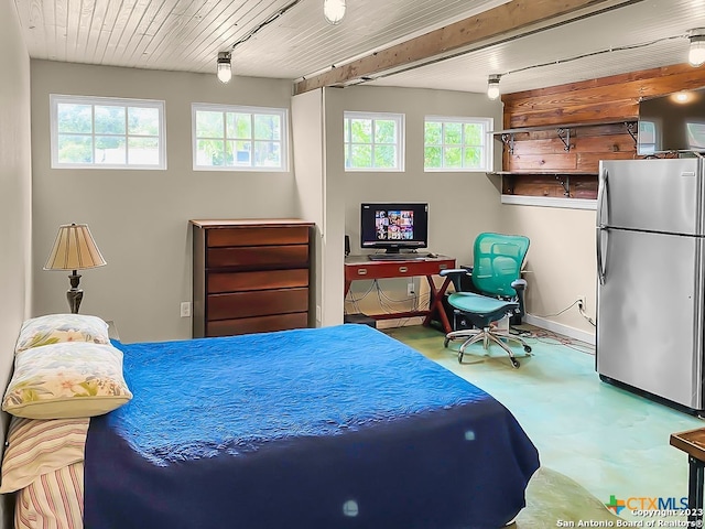 bedroom featuring concrete floors and stainless steel fridge