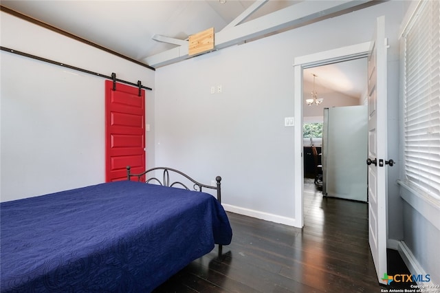 bedroom with lofted ceiling, a barn door, dark hardwood / wood-style floors, and stainless steel refrigerator