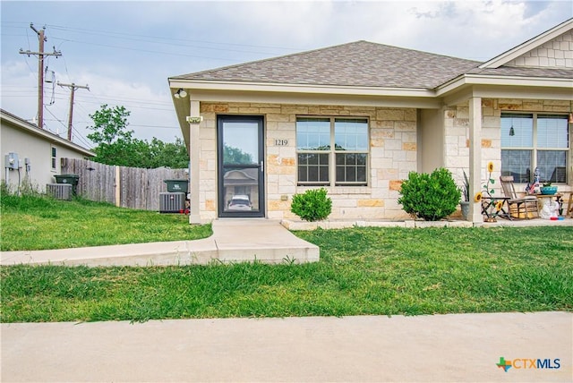1219 Honor Ln, Temple, TX 76501 - view of front of home featuring a shingled roof, stone siding, and central AC unit