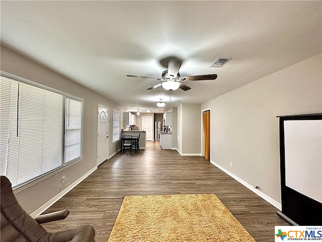 unfurnished living room with a textured ceiling, dark hardwood / wood-style floors, and ceiling fan