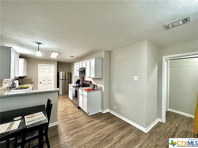 kitchen featuring dark hardwood / wood-style flooring, white cabinets, sink, appliances with stainless steel finishes, and decorative light fixtures