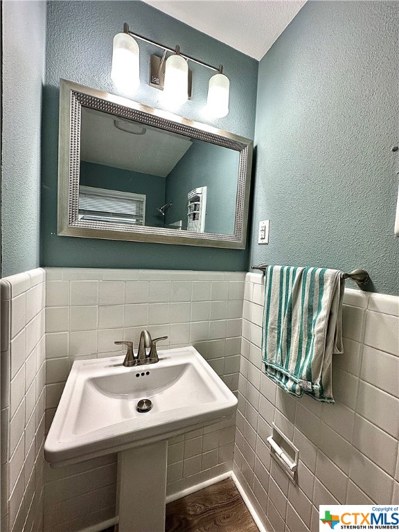 bathroom with tile walls and hardwood / wood-style flooring