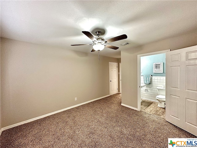 unfurnished bedroom with ensuite bathroom, ceiling fan, a textured ceiling, and carpet flooring