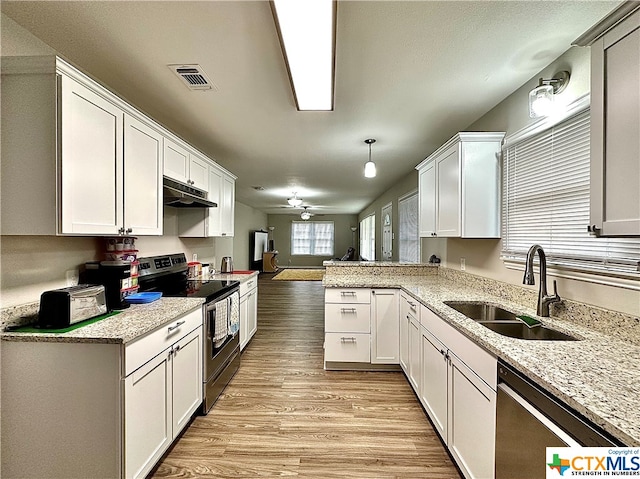 kitchen featuring kitchen peninsula, hanging light fixtures, sink, white cabinetry, and appliances with stainless steel finishes