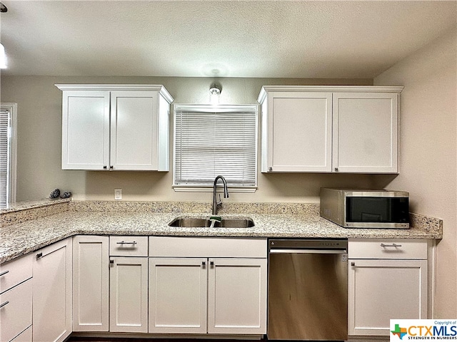 kitchen with white cabinetry, appliances with stainless steel finishes, sink, and light stone countertops