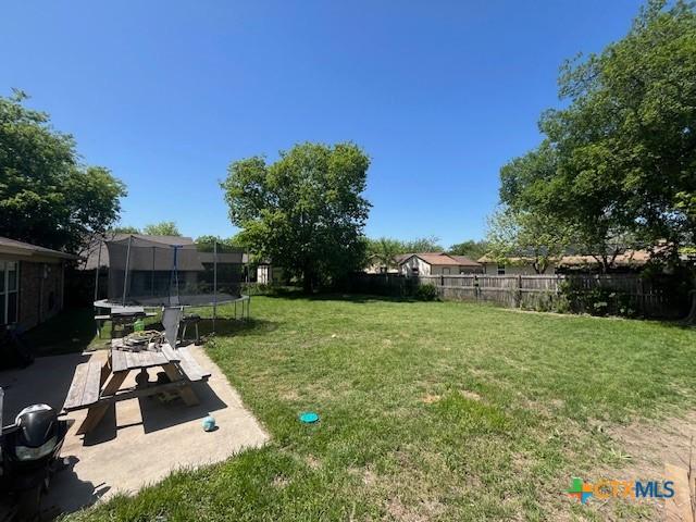view of yard with a trampoline, a patio area, and a fenced backyard