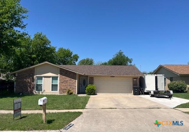 single story home featuring a garage, driveway, a front lawn, and brick siding