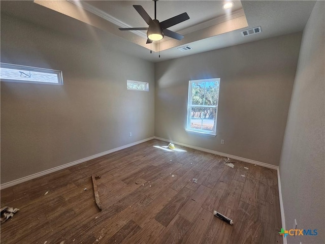 unfurnished room featuring wood finished floors, a raised ceiling, visible vents, and baseboards