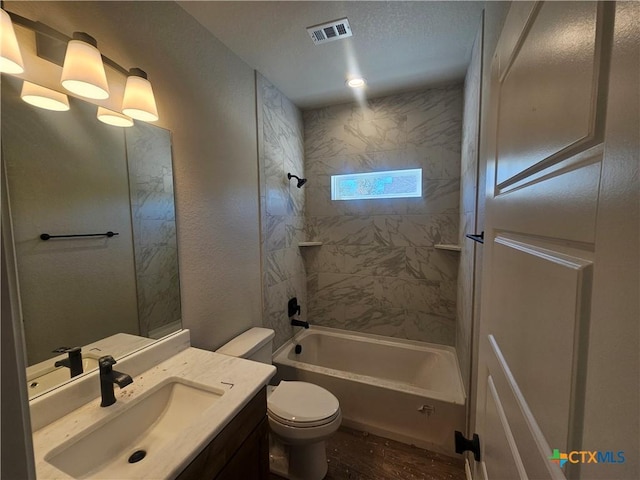 bathroom with visible vents, toilet, wood finished floors,  shower combination, and vanity