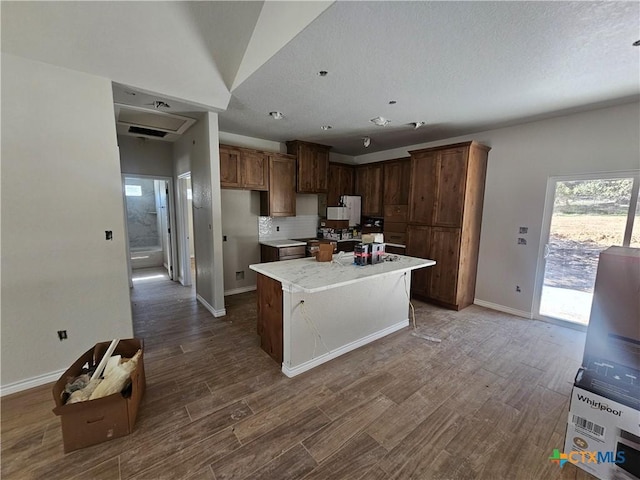 kitchen with tasteful backsplash, a kitchen island, and hardwood / wood-style floors