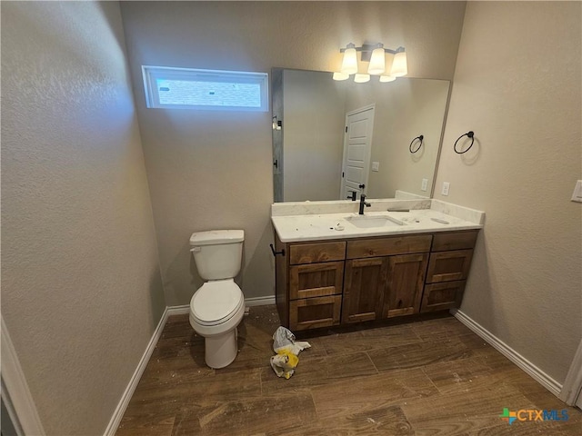 bathroom featuring toilet, wood finished floors, vanity, and baseboards