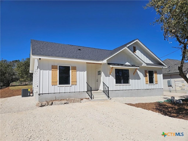 modern inspired farmhouse featuring roof with shingles, board and batten siding, and cooling unit