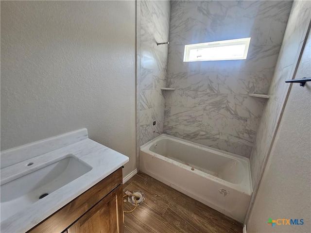 bathroom with hardwood / wood-style flooring, vanity, and tiled shower / bath