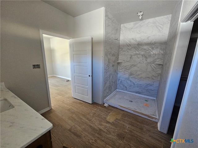 bathroom with vanity, tiled shower, and hardwood / wood-style floors