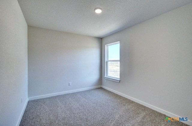 carpeted spare room with baseboards and a textured ceiling