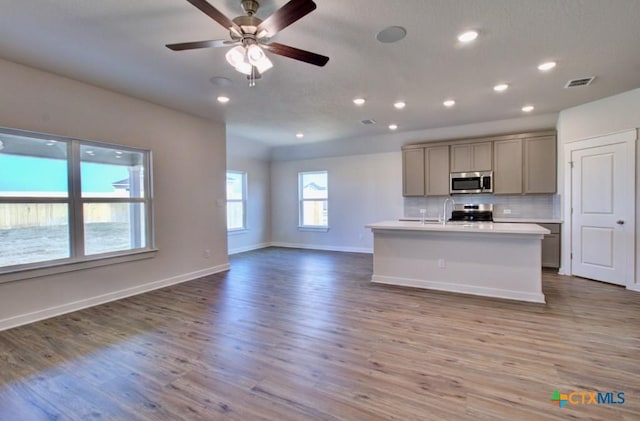 kitchen with visible vents, backsplash, open floor plan, gray cabinets, and stainless steel appliances