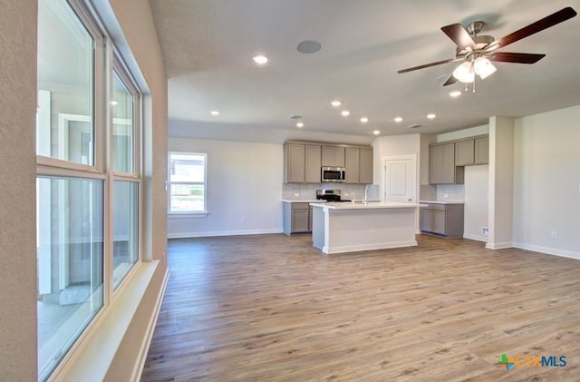 kitchen featuring stainless steel appliances, backsplash, gray cabinetry, and open floor plan