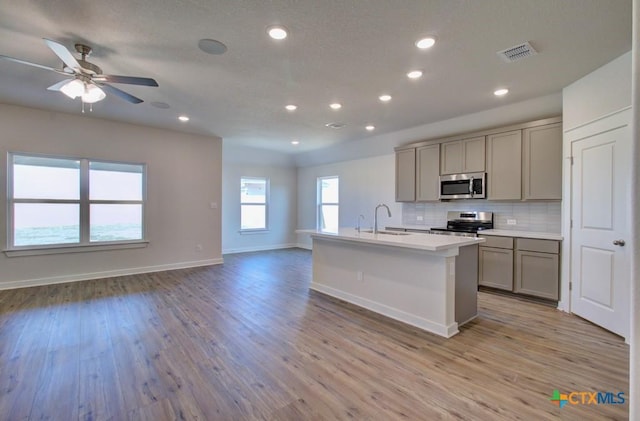 kitchen featuring visible vents, gray cabinetry, light wood-style floors, appliances with stainless steel finishes, and tasteful backsplash