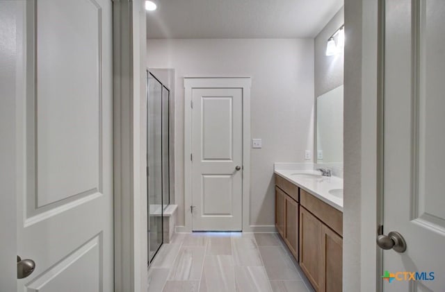 full bath with a shower stall, double vanity, and a sink