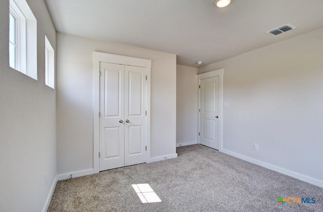 unfurnished bedroom with carpet, visible vents, and baseboards