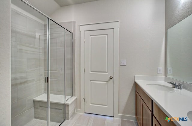 bathroom featuring a sink, baseboards, double vanity, and a shower stall