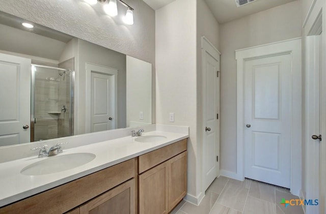 bathroom featuring a sink, baseboards, a stall shower, and double vanity