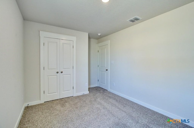 unfurnished bedroom featuring a closet, visible vents, carpet flooring, and baseboards