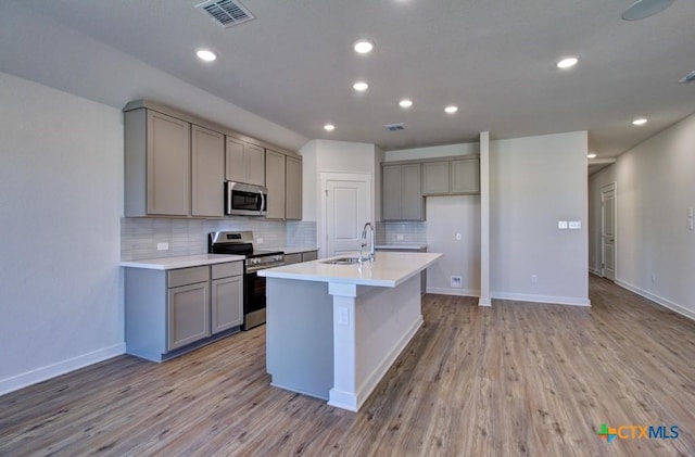 kitchen featuring visible vents, gray cabinetry, light wood-style flooring, a sink, and stainless steel appliances