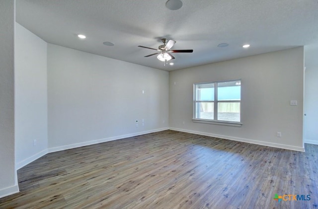 empty room featuring baseboards, wood finished floors, and a ceiling fan