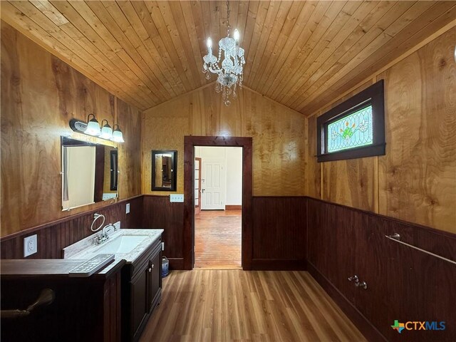 184 3rd St, Maxwell, TX 78656 - bathroom featuring wood walls, a chandelier, wood finished floors, a wainscoted wall, and vaulted ceiling