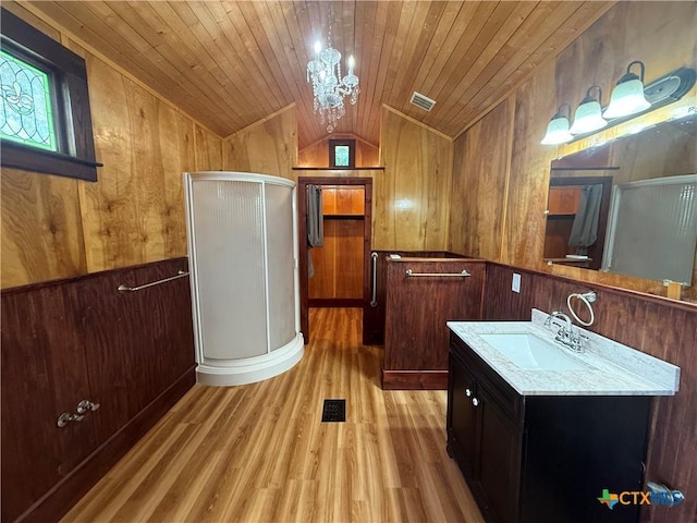 184 3rd St, Maxwell, TX 78656 - bathroom with lofted ceiling, wooden walls, a shower stall, vanity, and wood finished floors