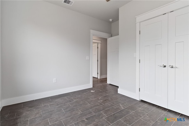 unfurnished bedroom with dark hardwood / wood-style floors and a closet