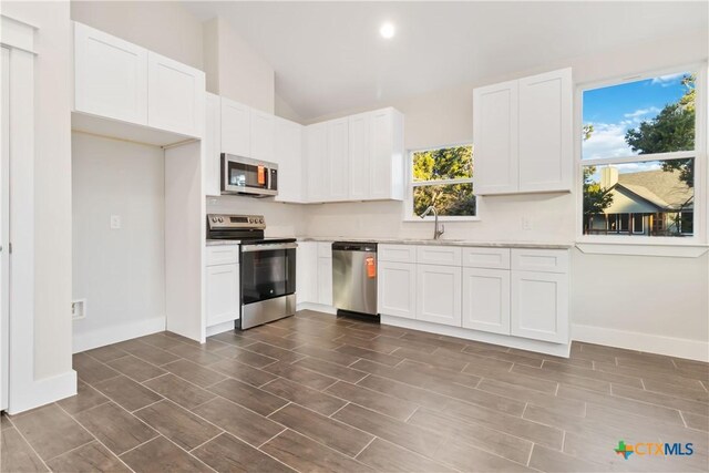 kitchen with appliances with stainless steel finishes, white cabinetry, plenty of natural light, and sink