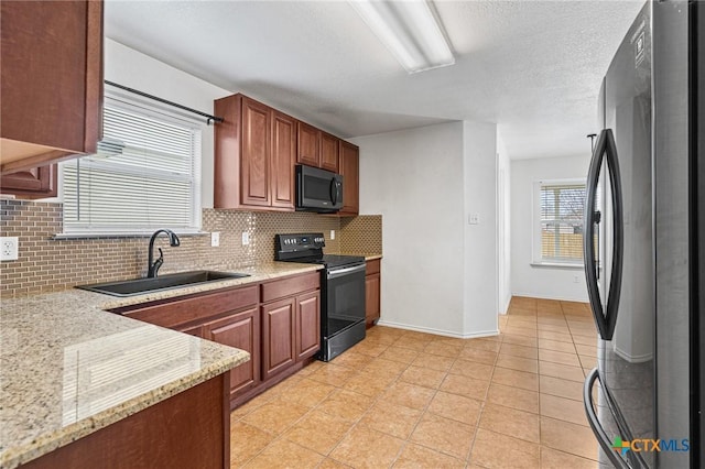 kitchen featuring backsplash, black appliances, sink, light tile patterned floors, and light stone counters