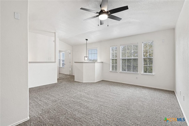 unfurnished living room with ceiling fan, a wealth of natural light, carpet, and vaulted ceiling