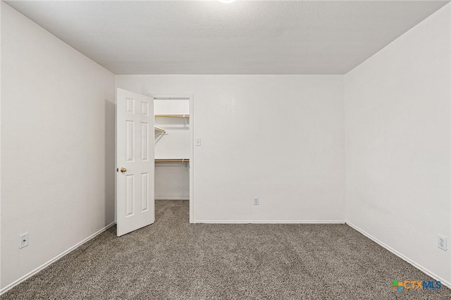 unfurnished bedroom with a closet, a spacious closet, and carpet flooring