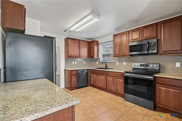 kitchen featuring a textured ceiling, stainless steel appliances, decorative backsplash, and sink